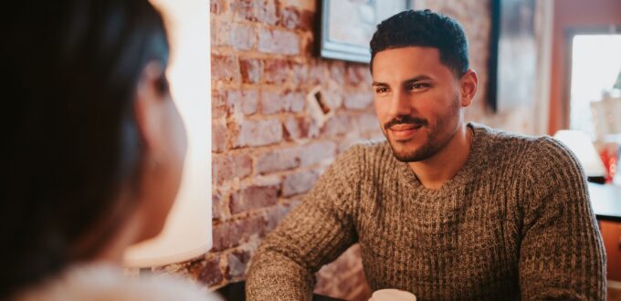 Couple smiling and talking over coffee at a cafe, representing the three dates stage of the 3-3-3 dating rule