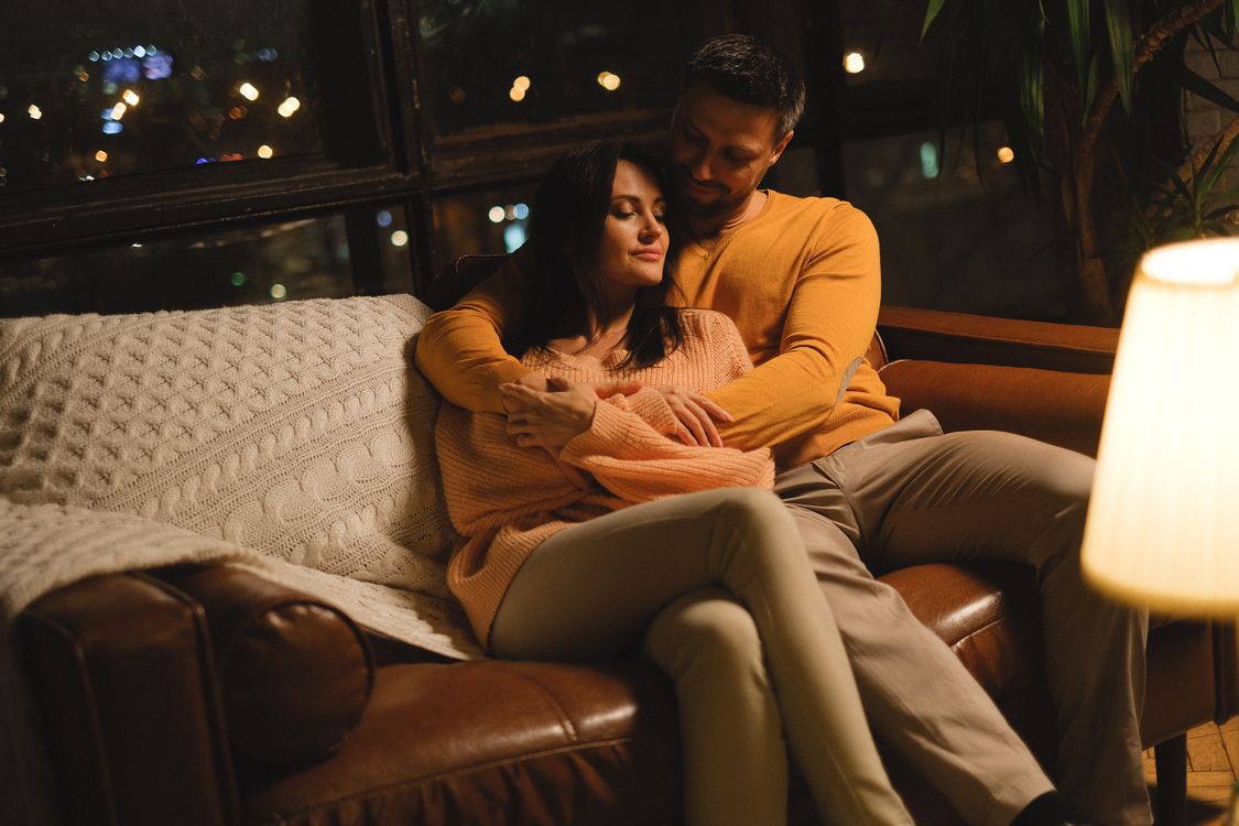 Couple embracing warmly on a couch, illustrating the trust and intimacy at the center of fetish psychology