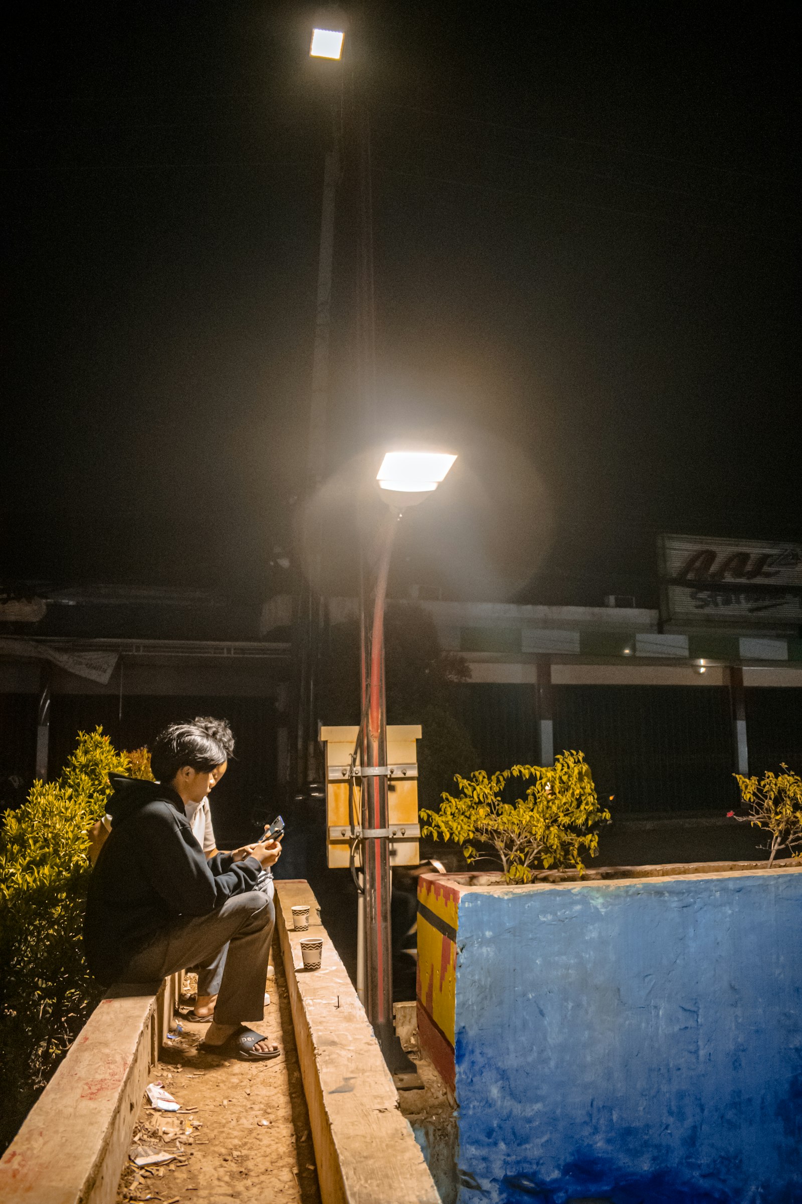 Man sitting alone at night checking his phone for a reply while online dating