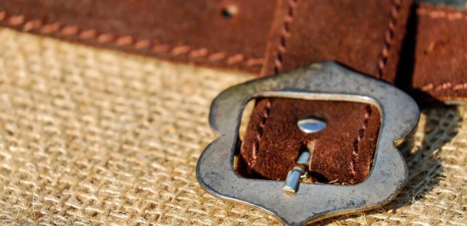 Coiled leather belt with metal buckle, symbolizing the leather implements at the center of impact play