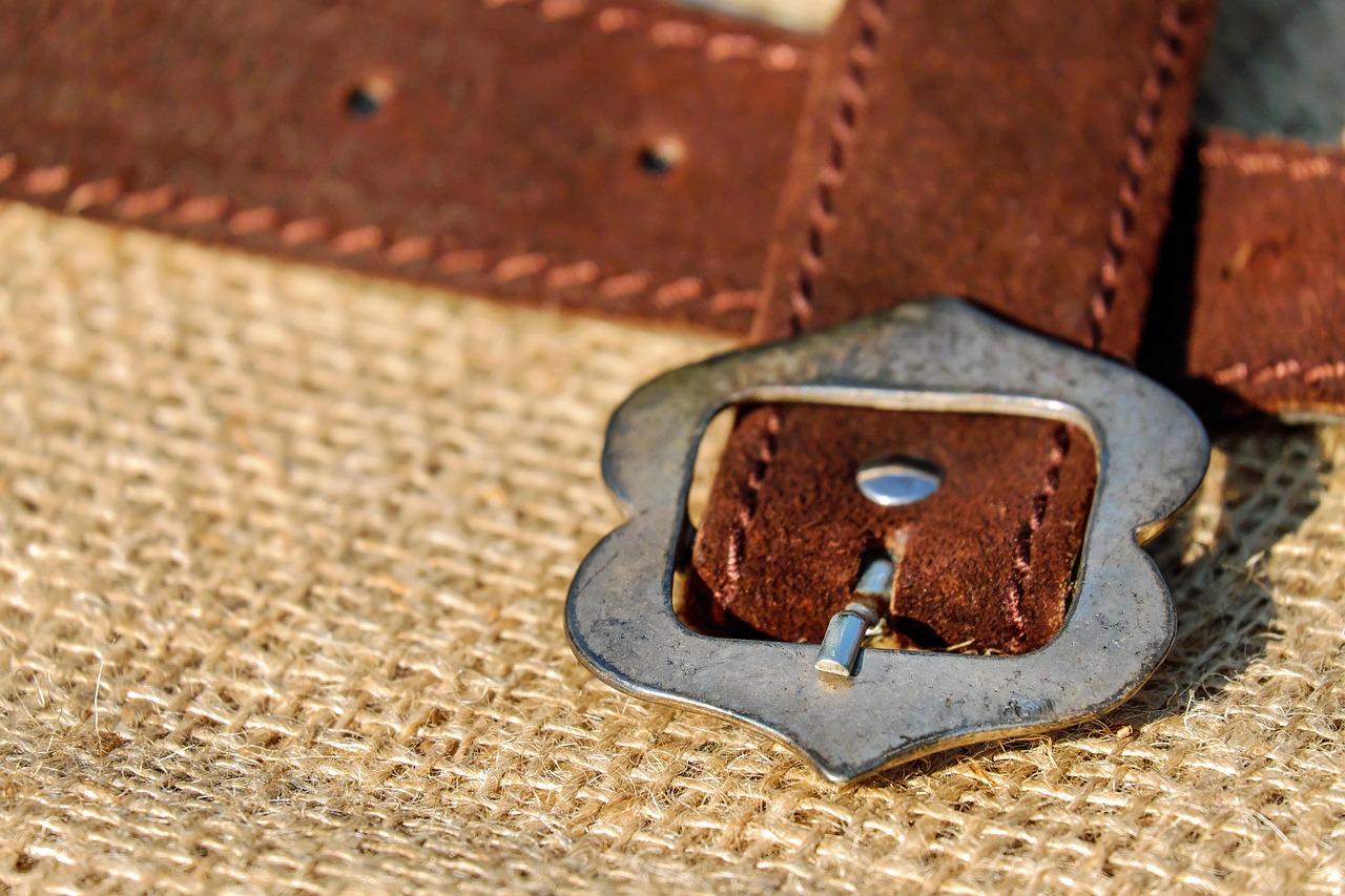 Coiled leather belt with metal buckle, symbolizing the leather implements at the center of impact play