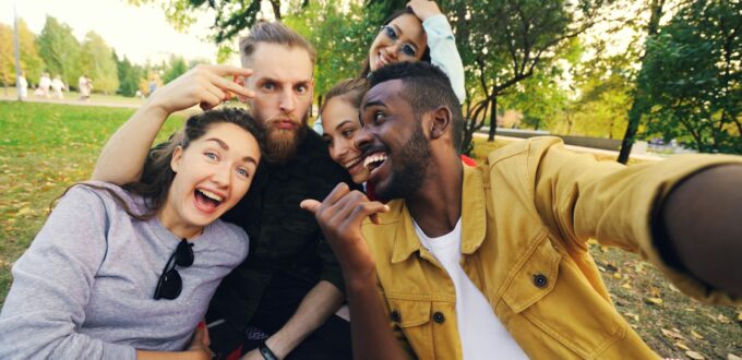 A group of friends taking a selfie together on a blanket in a park, a picture of dating moving offline and into real social circles