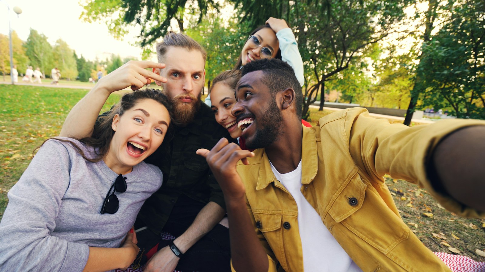 A group of friends taking a selfie together on a blanket in a park, a picture of dating moving offline and into real social circles