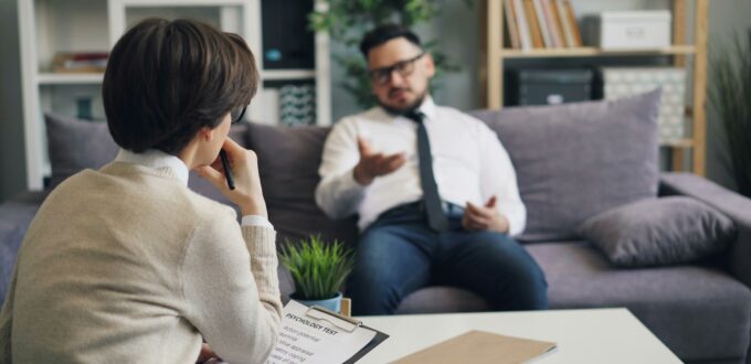A man and a woman sitting on a couch in a serious conversation, the kind of talk a situationship keeps getting put off