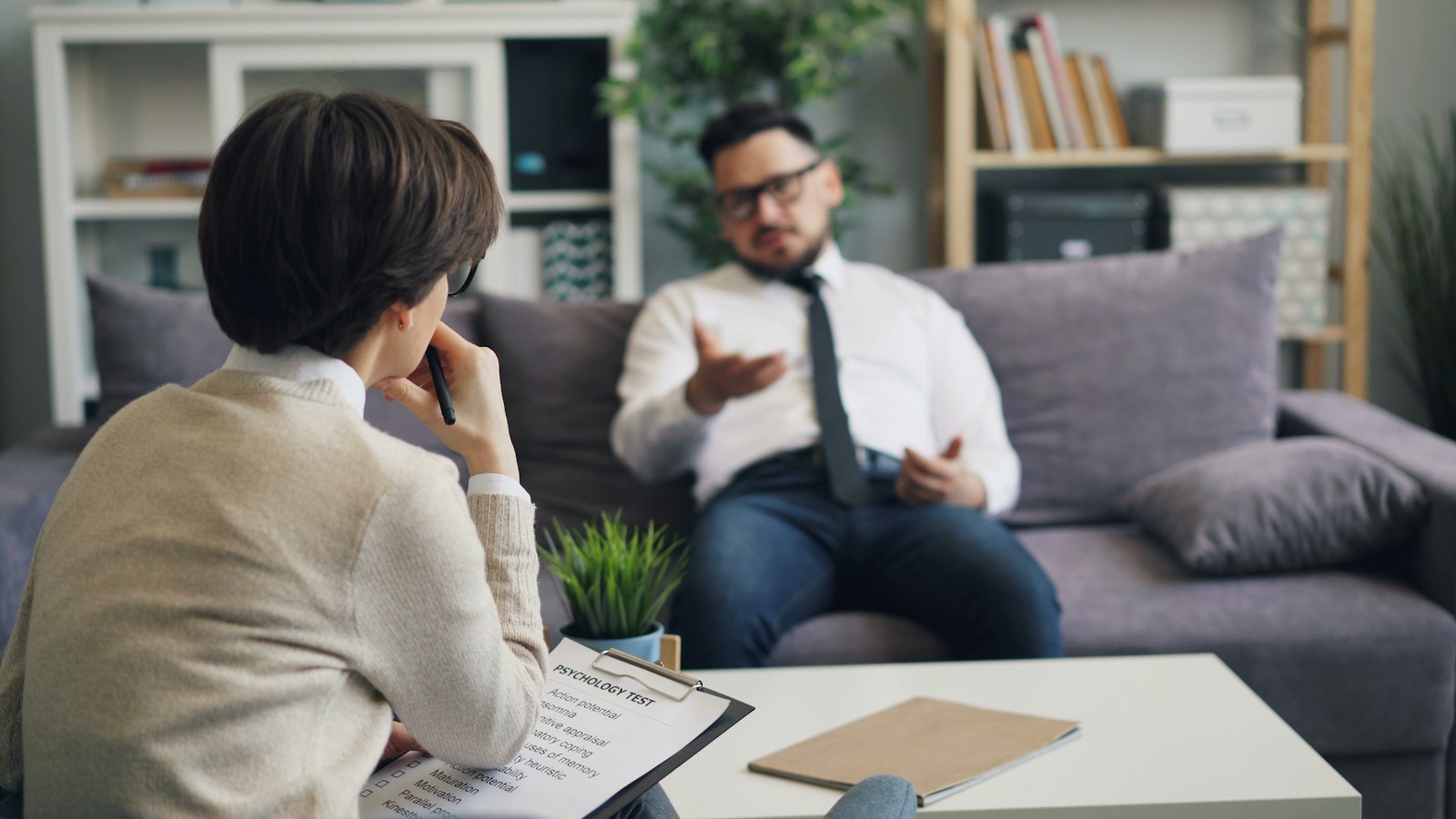 A man and a woman sitting on a couch in a serious conversation, the kind of talk a situationship keeps getting put off